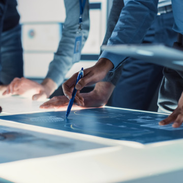 Engineer,,Scientists,And,Developers,Gathered,Around,Illuminated,Conference,Table,In